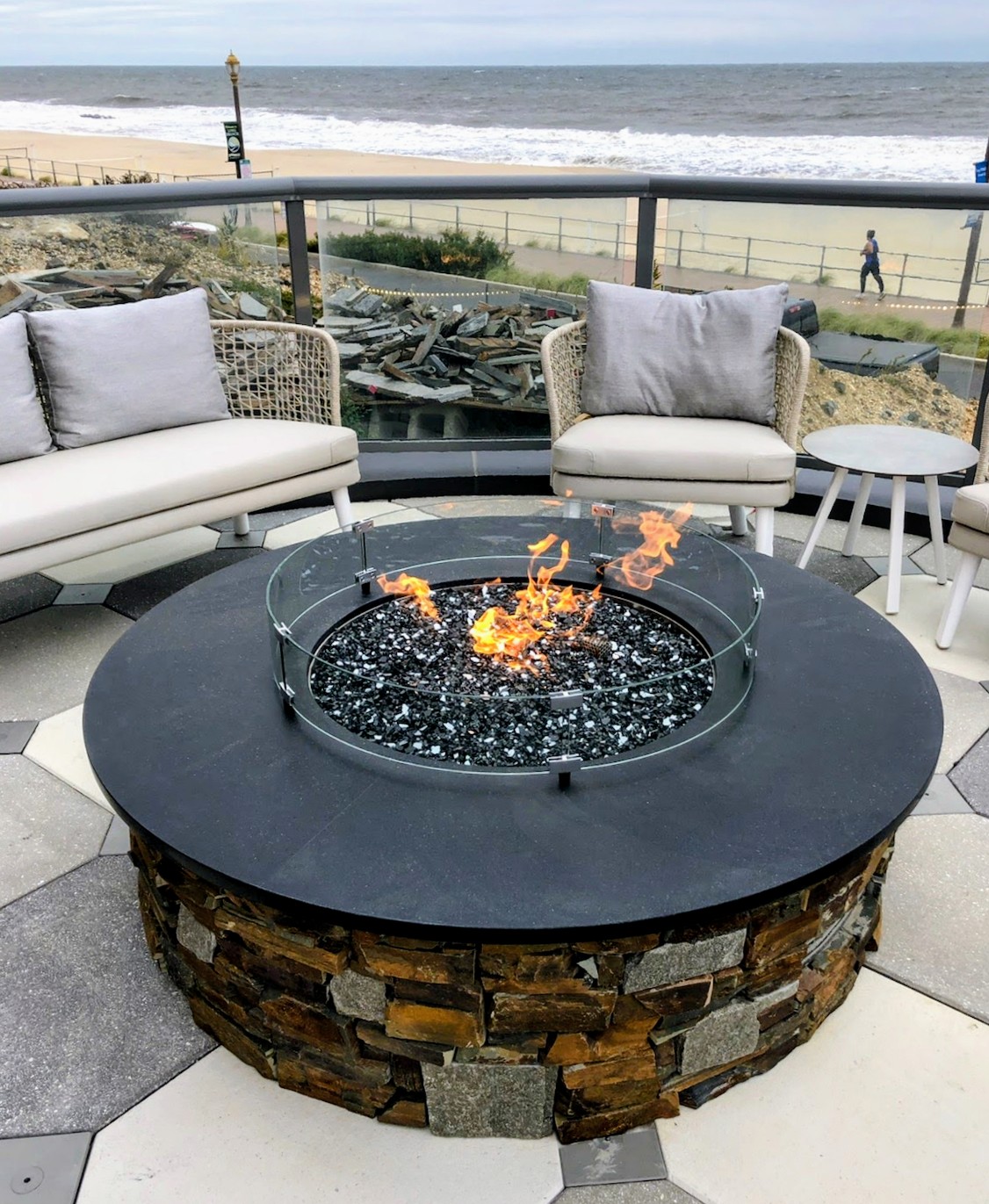 Custom outdoor stone fire pit with glass media and oceanfront seating area